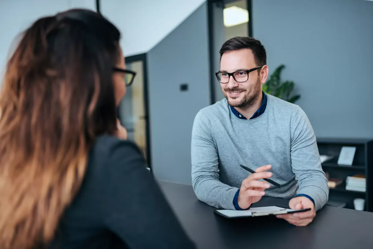 a man sitting at a table talking to a woman.